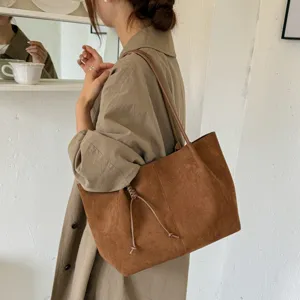 Detail shot of a brown suede shoulder tote bag, large capacity and vintage design for women.