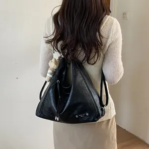 Detail view of black leather hobo backpack tote bag with cute bear pendant and metal tag.