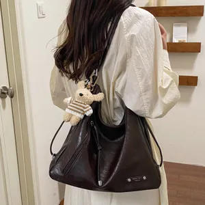 Detail view of large capacity dark brown hobo shoulder bag with cute knitted bear charm.