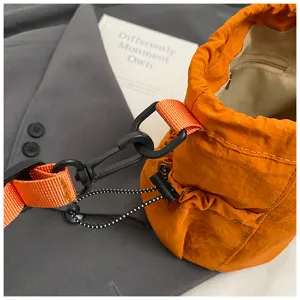 Close up of orange nylon bucket bag detail, showing adjustable strap and buckle hardware.