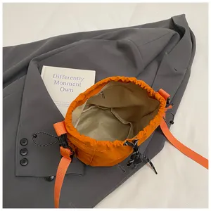 Nylon bucket crossbody bag in bright orange with adjustable drawstring and wide strap detail
