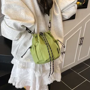 Green nylon drawstring crossbody bucket bag with speckled cords for daily outdoor wear.