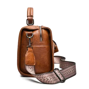 Sac à main rétro en cuir marron avec sangle large à motifs, fourre-tout élégant.