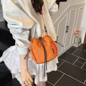 Niche design nylon crossbody bucket bag, trendy Japanese style with drawstring and mesh pockets.