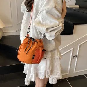 Detailed view of the trendy nylon drawstring bucket crossbody bag in vibrant orange, outdoor style.