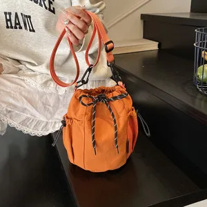 Orange nylon bucket bag detail, showing adjustable crossbody strap and drawstring closure design.