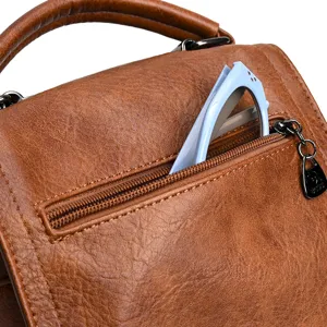 Vue détaillée d'un sac à main en cuir marron vintage avec poche zippée et texture élégante.