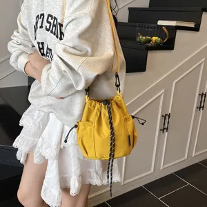 Nylon bucket bag detail, casual yellow crossbody bag with drawstring and side mesh pocket.