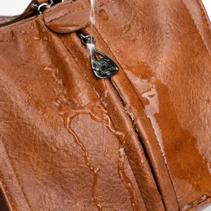Détail de sac à bandoulière pour femme vintage montrant texture cuir marron imperméable.