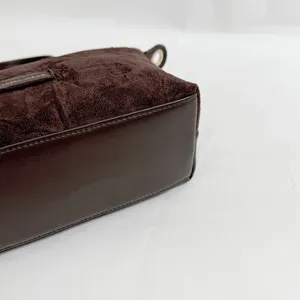 Detail view of brown suede texture handbag with leather bottom, compact retro design.