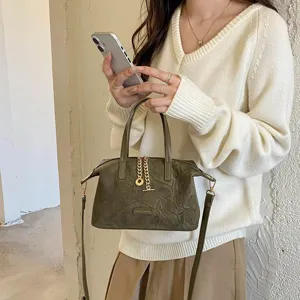 Minimalist suede handbag detail view, showing vintage green crossbody design and metallic chain accent.