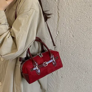 Nahaufnahme einer weinroten Vintage-Wildleder-Boston-Handtasche mit feinen Details.