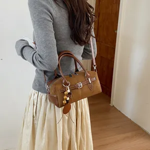 Detailaufnahme einer braunen Retro-Wildleder-Boston-Tasche mit Riemen und Perlendekor.