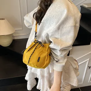 Close-up detail of yellow nylon bucket bag with convenient drawstring and mesh pocket.