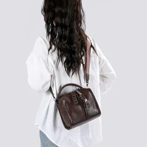 Vue détaillée du sac à bandoulière en cuir marron vintage porté par le mannequin de dos.