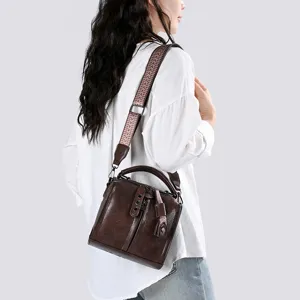 Vue détaillée du sac à bandoulière vintage en cuir marron avec large sangle stylée.