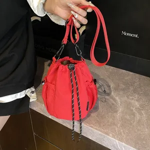 Red nylon drawstring bucket crossbody bag, stylish casual outdoor sports bag with mesh side pockets.