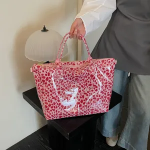 Primo piano della borsa tote leopardata rosa, tessuto lucido e dettagli di stampa raffinati.