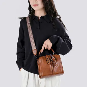 Gros plan détail du sac à bandoulière en cuir marron vintage pour femmes avec large sangle à motifs.