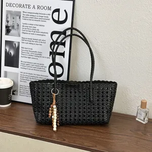 Black hollow woven tote bag detail showing intricate grid pattern, scalloped edge, and chic charm.