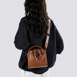 Vue détaillée du sac bandoulière en cuir marron rétro avec large sangle à motifs.