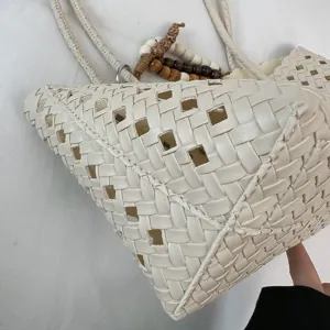 Close-up of a stylish white woven cutout shoulder tote bag showing exquisite texture and detail.