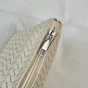 Close-up shot of beige woven leather bag detail with zipper and exquisite texture design.