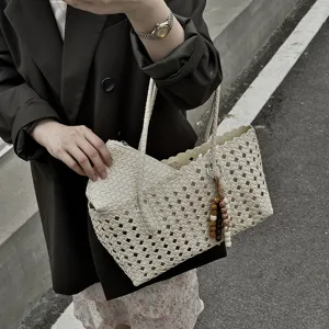 Detailed view of the woven hollow out tote bag with inner pouch and chic beaded charm.
