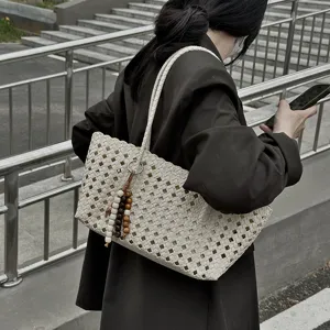 Detailed close-up shot of woven tote bag showcasing hollow design and stylish bead charm.