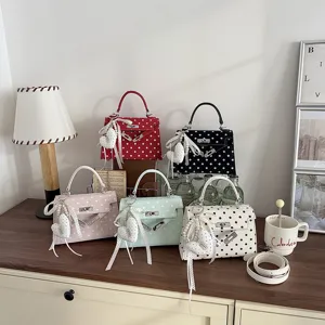 Detail shot of stylish polka dot Kelly handbag with heart charm and ribbon on elegant desk.