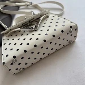 White black polka dot women handbag detail shot, elegant chic shoulder crossbody bag style.