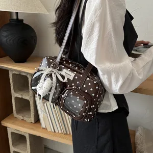 Brown polka dot bowling bag detail showcasing clear front pockets and bow accessory.