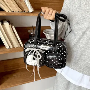 Detailed view of black white polka dot bowling bag with clear front pockets and charm.