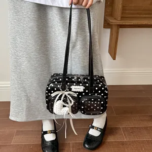Black and white polka dot bowling handbag with dual straps, front pockets and cute bow pendant.