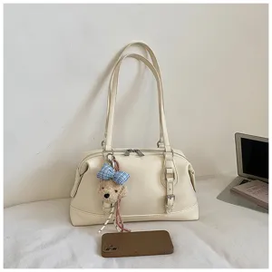 Detail shot of cream white vintage shoulder bag with cute teddy bear charm and sleek leather design.