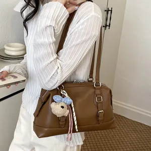 Detailed view of a brown vintage shoulder bag worn by a model in a clean indoor setting.