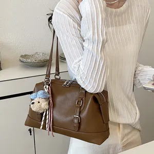 Brown vintage large capacity underarm shoulder bag with cute bear pendant detail.