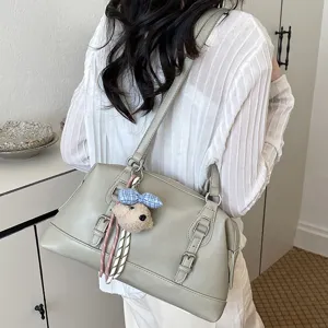 Detail view of a vintage light grey shoulder bag worn on shoulder with cute bear pendant