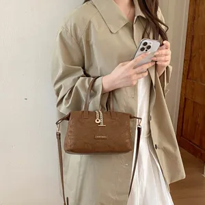Brown faux suede handbag detail, vintage minimalist design, stylish metal charm and shoulder strap.