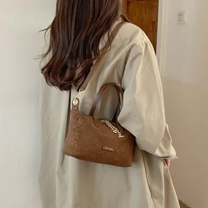 Brown suede small handbag detail shot, featuring metal chain decor and versatile retro style design.
