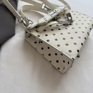 Polka dot handbag detail, chic white and black design with classic structured top handle.