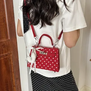 Red white polka dot Kelly shoulder bag detail view with cute ribbon bow and heart charm.