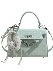 Mint green polka dot handbag with top handle, turn-lock closure and cute heart charm.
