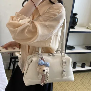 Detail view of the vintage white leather underarm shoulder bag with a cute bear plush charm.