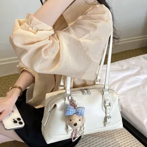 Detail view of a vintage white shoulder bag with cute pendant, perfect for daily casual commuting.