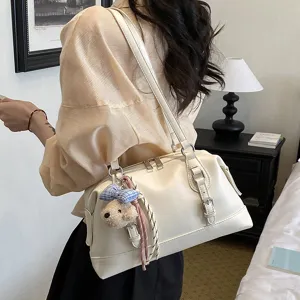 Detail shot of the cream white retro shoulder bag with cute bear charm and metal hardware.