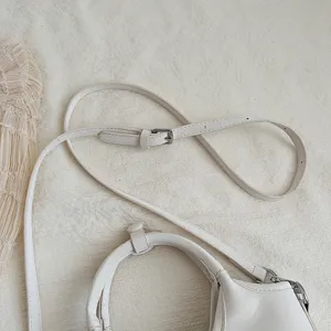 Nahaufnahme von Schulterriemen und Griff einer minimalistischen weissen Beuteltasche.
