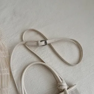 Nahaufnahme der minimalistischen beige Damentasche Schulterriemen und Knotengriff.