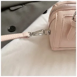 Close-up detail of pink patent leather Boston bag hardware, showing metal clasp and texture.