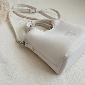 Elegantes weißes Leder-Eimer-Taschen-Detail mit feiner Textur, Henkel und Umhängegurt.